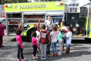 A group of children standing in front of a fire truck.