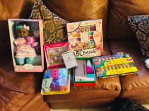 A brown couch with several boxes of toys and books.