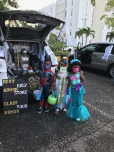 Two children dressed as superheroes in front of a trunk.